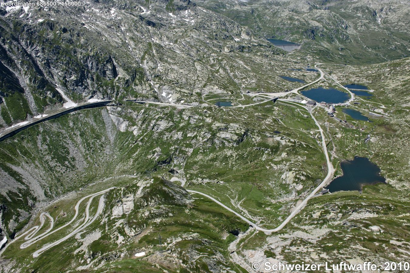 Ospizio San Gottardo, 2091 m.ü.M. (Position: 2'686'600.83, 1'156'692.44) - Bildmitte rechts: Passhöhe; Stausee oben rechts: Lucendro-Stausee; Kurvenreiche Strasse links: Tremola